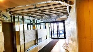 Lobby with plastic sheeting and exposed ceiling.