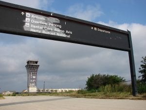 The now vacated Robert Mueller Municipal Airport in Austin, Texas. An old sign pointed to the direction for arrival pick-up in the foreground while an old tower stands in the back.