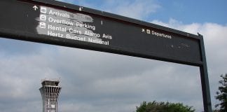 The now vacated Robert Mueller Municipal Airport in Austin, Texas. An old sign pointed to the direction for arrival pick-up in the foreground while an old tower stands in the back.
