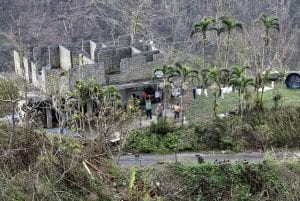 People wave to a helicopter (not seen) in Puerto Rico after Hurricane Maria washed out roads.