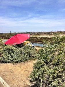 A red umbrella is part of a homeless encampment along the Santa Ana river trial in California.