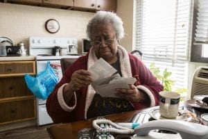 An African-American woman sits at her table and looks through photographs.