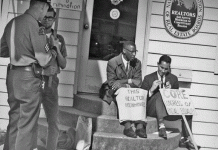 Two men sit on a stoop with signs during a fair housing protest in Seattle, Washington, in 1964.