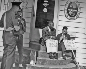 Two men sit on a stoop with signs during a fair housing protest in Seattle, Washington, in 1964.