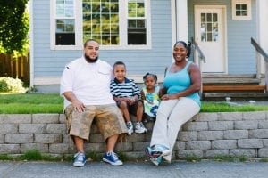 A family of four sit outside their home in Portland. Portland's preference policy gives priority for homeownership opportunities funded by the city’s housing bureau to residents who were displaced.