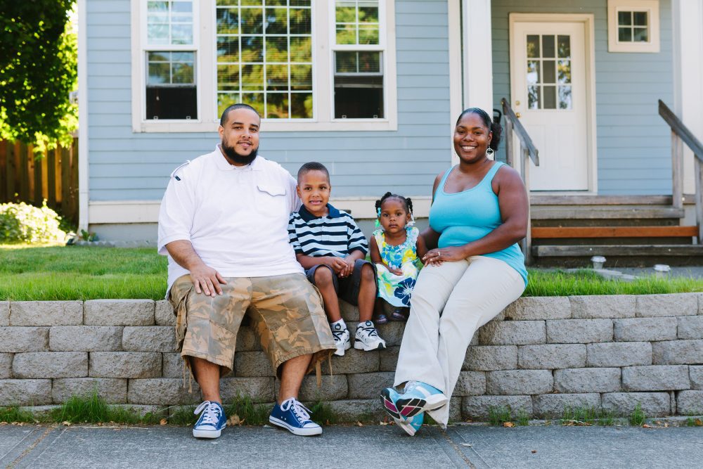 A family of four sit outside their home in Portland. Portland's preference policy gives priority for homeownership opportunities funded by the city’s housing bureau to residents who were displaced.