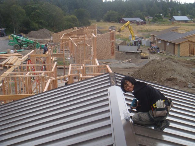 A woman puts on metal roofs on one of the houses