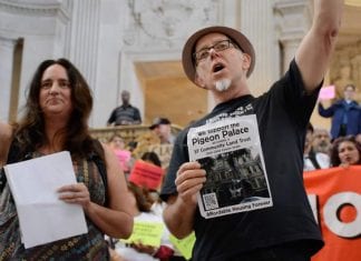 Carin McKay and Chris Carlsson at City Hall during a Mission No Eviction protest in 2015. Charlsson holds a sign that reads "We support the Pigeon Palace becomming a SF Community Land Trust."