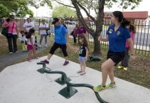 Several residents, as well as some children, enjoy outside exercise equipment.