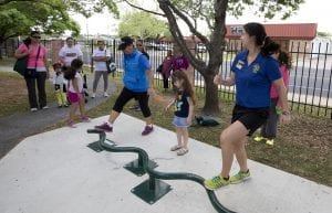 Several residents, as well as some children, enjoy outside exercise equipment.