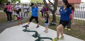 Several residents, as well as some children, enjoy outside exercise equipment.