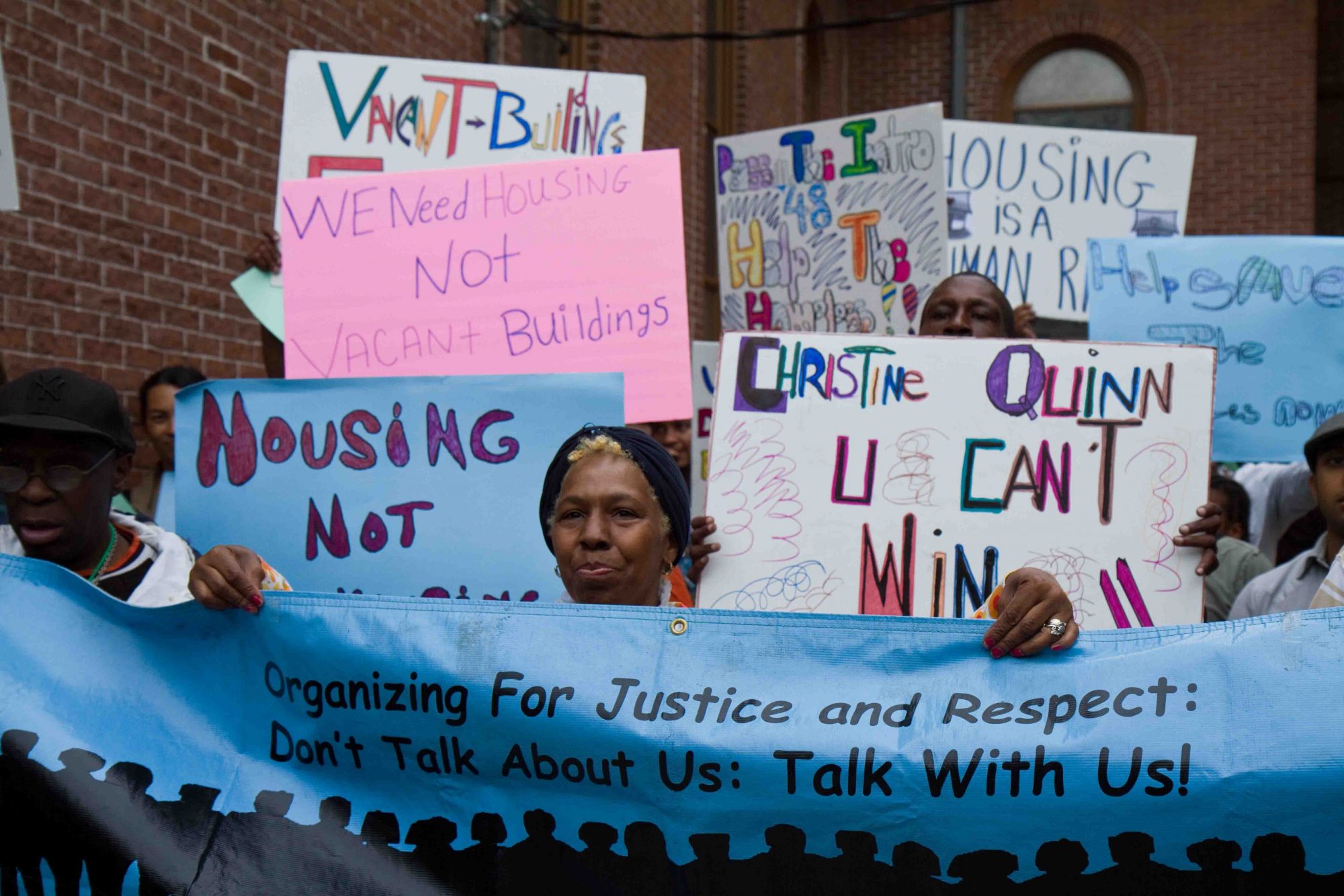 Members of Picture the Homeless protest outside councilwoman's office with signs that read "Organizing for Justice and Respect" and "We Need Housing, not Warehousing."