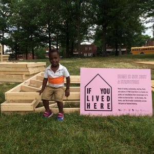 little boy sits next to sign