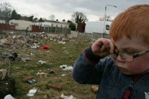 A young boy with glasses rubs his eyes outside in Dale Farm, which was once the site of the largest Irish Traveller concentration until families were evicted in 2011. A health impact assessment helped house this indigenous group, which accounts for 1 percent of the total population in Ireland.