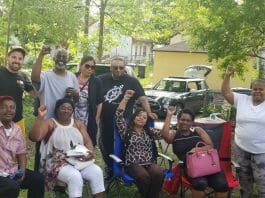 North Minneapolis tenants pose together with their fists in the air during a barbecue