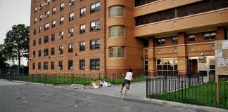A child rides her bike outside of Ocean Bay (Bayside) Apartments in Far Rockaway, the first housing project in New York City to take part in the RAD program, as well as the largest RAD-funded project in the country.