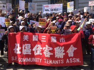 Members of the San Francisco Community Tenants Association hold a large red resign during a rally against SB 827.