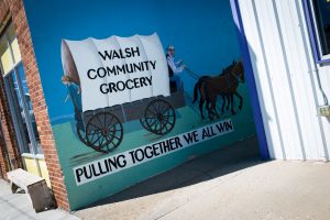 A painting that reads "Walsh Community Grocery: Pulling Together We All Win."