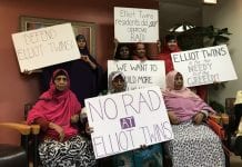 Women hold up signs that read "No RAD at Elliot Twins" and others.
