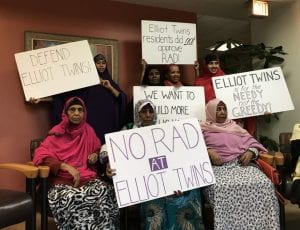 Public housing residents hold up signs that read "No RAD at Elliot Twins" and others.