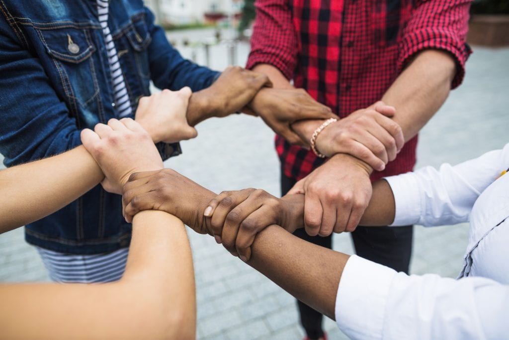 four people linking hands together