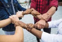 four people linking hands together