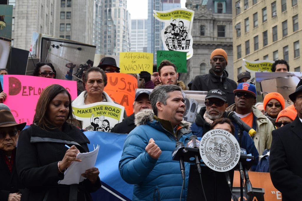 A man, who participated in a community organizing program, speaks at a rally and is surrounded by people holding sign.