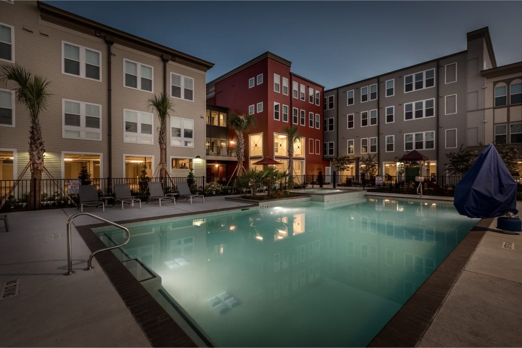 A pool sits in front of three large buildings are part of the Villas on the Strand housing complex.