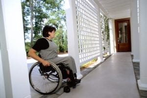 a woman with disabilities approaches the door of a house while in a wheelchair 