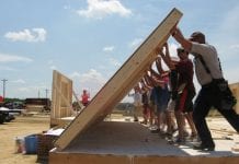 A group works to raise a wall as part of the Self-Help Housing Program.