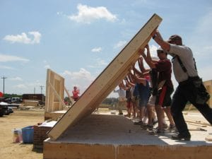 A group works to raise a wall as part of the Self-Help Housing Program.