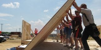 A group works to raise a wall as part of the Self-Help Housing Program.