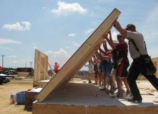 A group works to raise a wall as part of the Self-Help Housing Program.