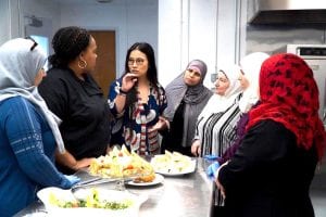 As part of a CultureBank Dallas initiative, a group of women speak with one another while eating.