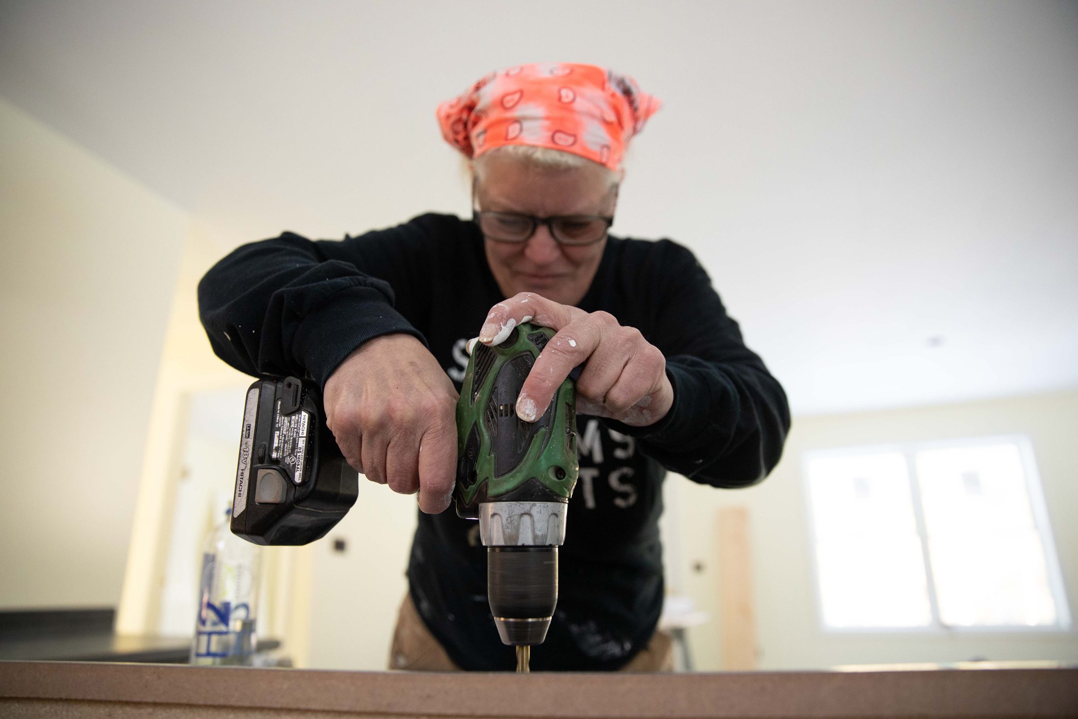 As part of a self-help housing program, a Main woman uses an electric screwdriver to build her home.