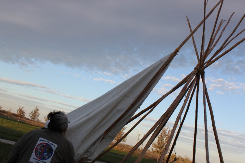 A woman puts up a tipi.