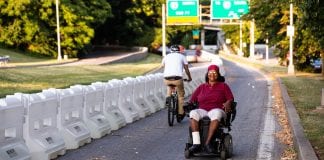 A woman wearing sitting in a motorized wheelchair smiles as she navigates her way up a temporary path in Baltimore.