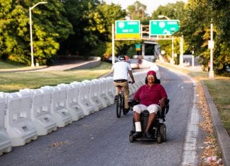 A woman wearing sitting in a motorized wheelchair smiles as she navigates her way up a temporary path in Baltimore.