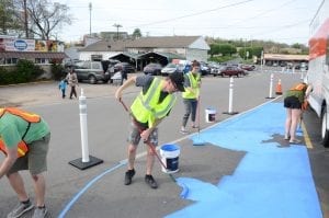 A group paints a blue temporary walking path.