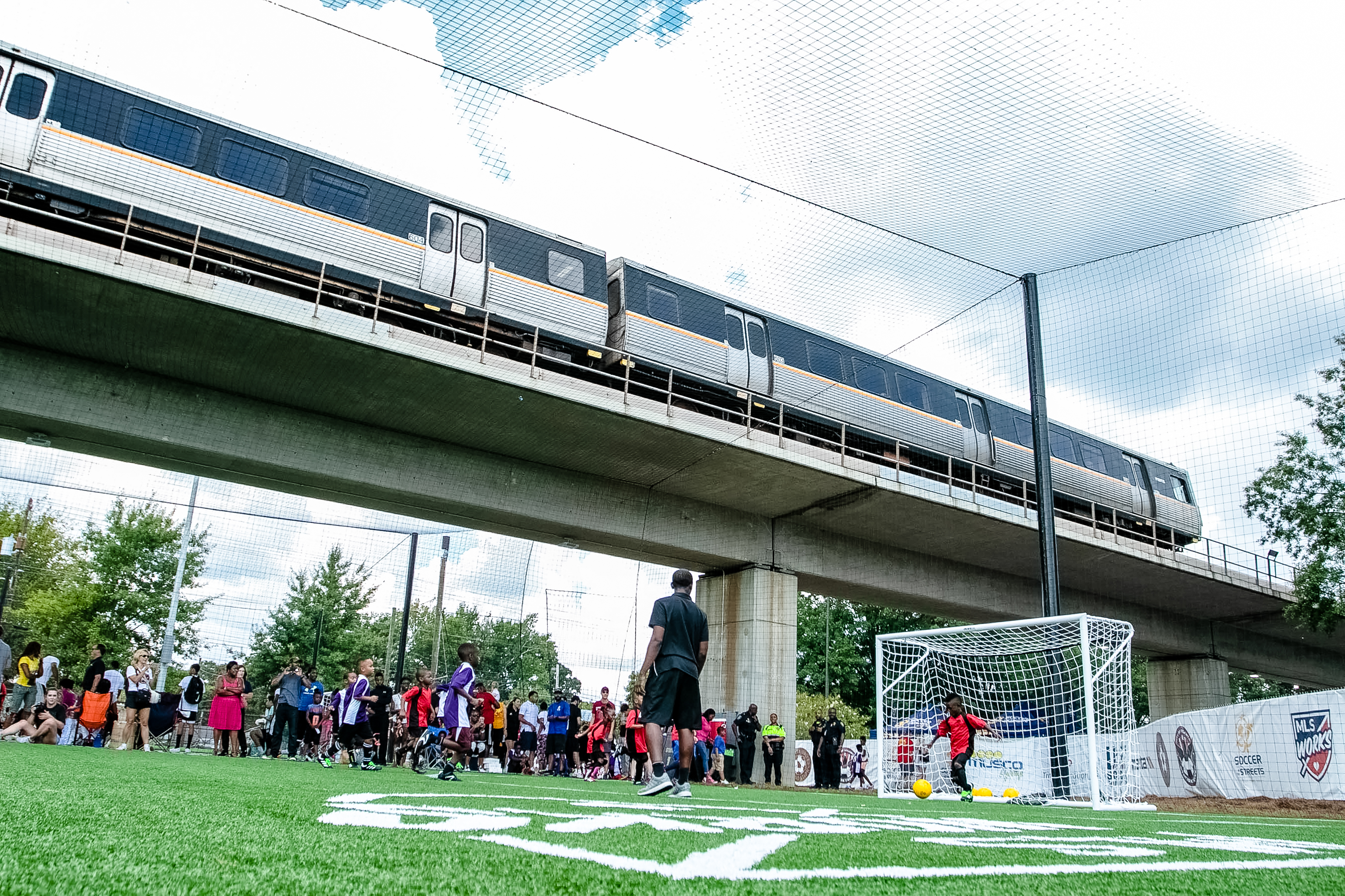 A youth soccer game played at the opening of StationSoccer-West End. A train can be seen above the field.