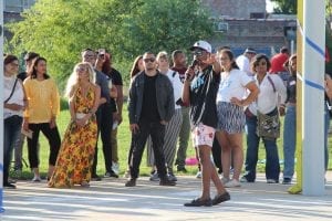 A man wearing a baseball cap and glass holds a microphone as he speaks to a group of people outside during a BBQ event celebrating the passage of SB 2090, which expands voting access and education efforts in Illinois jails.