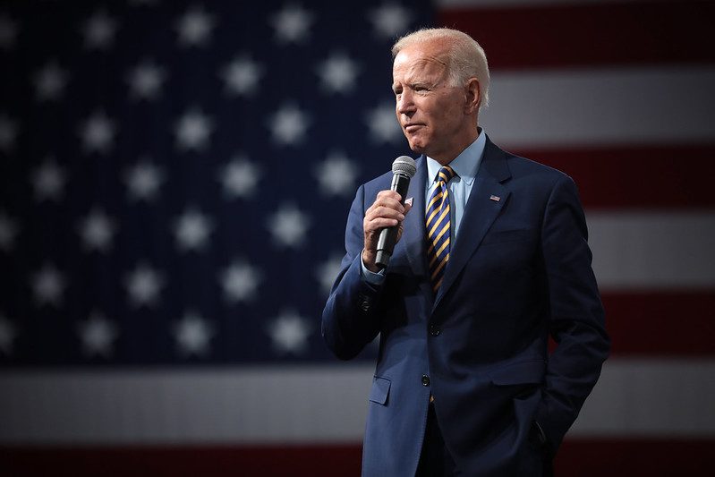 Vice President Joe Biden stands with a microphone in his hand in front of an American flag at an Iowa forum August 2019.