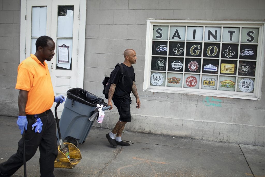 A man in black shorts and a black T-shirt pulls a garbage can on the sidewalk. Bobby Parker, an essential worker during the COVID-19 pandemic, was illegal evicted from his home for paying rent late.