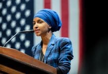 Rep. Ilhan Omar, who stands at a podium in front of an American flag, has proposed legislation that would cancel rents and individual mortgage payments nationwide to deal with the COVID-19 crisis.