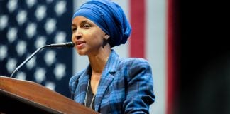 Rep. Ilhan Omar, who stands at a podium in front of an American flag, has proposed legislation that would cancel rents and individual mortgage payments nationwide to deal with the COVID-19 crisis.