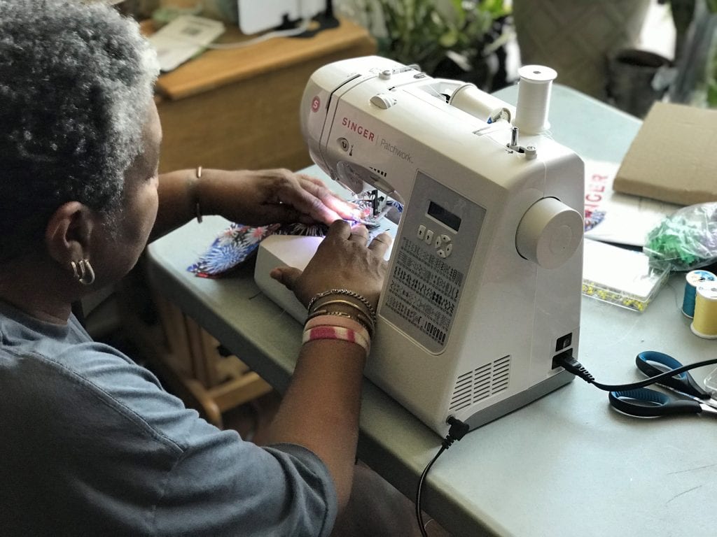 A woman on sews masks on a sewing machine