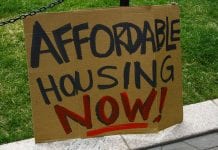 homemade cardboard sign says "Affordable Housing Now!"