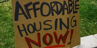 homemade cardboard sign says "Affordable Housing Now!"