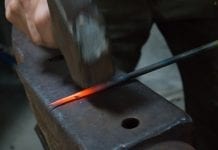 Blacksmith hammering iron on anvil
