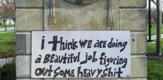 handpainted sign says "I think we are doing a beautiful job figuring out some heavy shit"